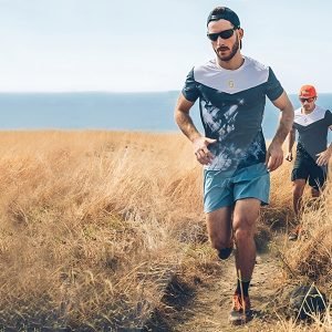 Men running together with Anchor Sunglasses Straps on a sunny day by the ocean.
